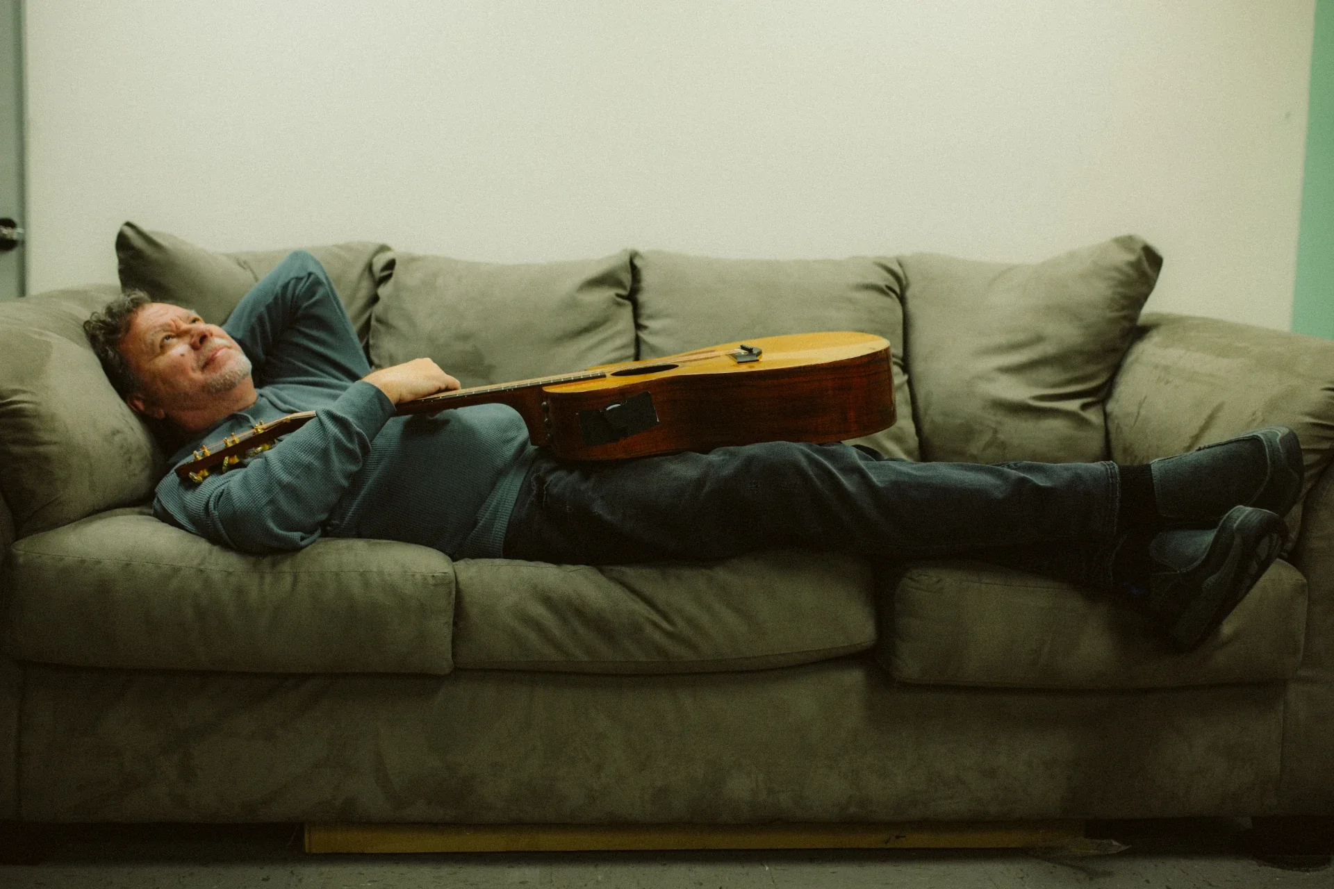 Louis Brittz relaxing on a sofa with his guitar
